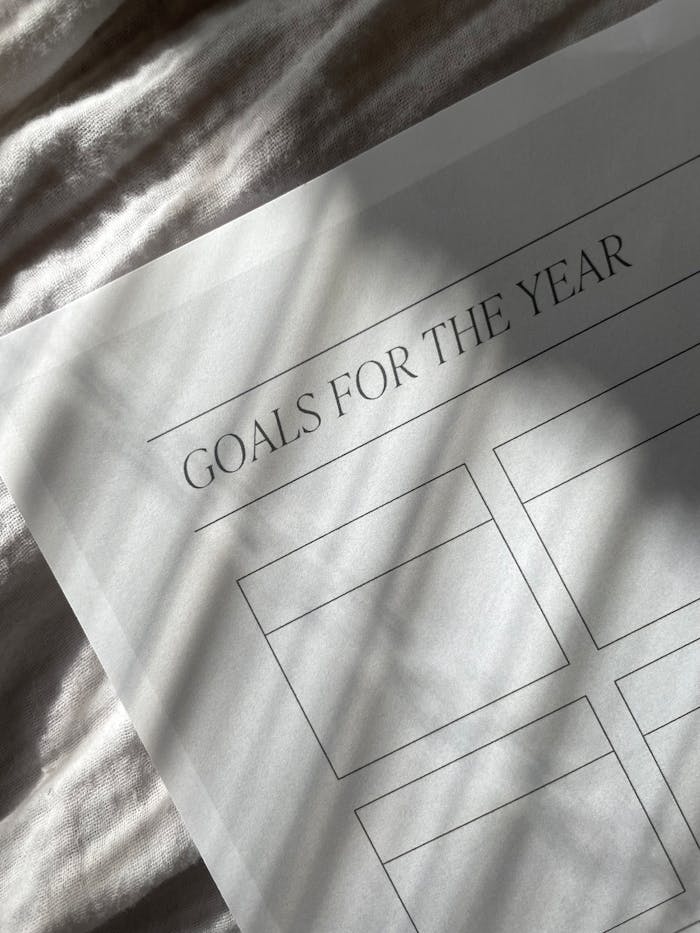 pexels photo 16037850 Close-up of a yearly goals planner sheet with blank spaces, captured in artistic shadow lighting.